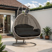 LeisureMod Black Wicker 2 Person Egg Swing Chair with Beige Stand and Cushions – Double Hanging Hammock Lounge for Patio, Indoor & Outdoor Use
